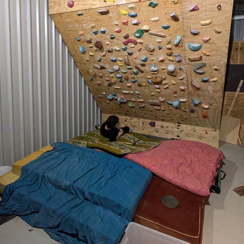 Mattresses and bouldering crash pads for padding under a climbing wall